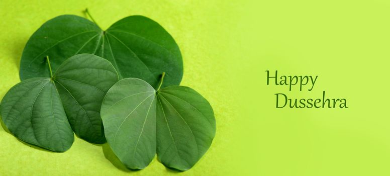 Indian Festival Dussehra, showing golden leaf and flowers on green background. Greeting card.