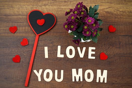 I love you mom wording with pink flower on old wooden background, Mother's day concept.