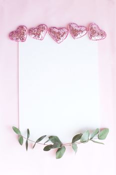 Background with copy space blank on pink background with pink glittered hearts, eucalyptus branch. White paper top view, flat lay, minimal style. Moke up card