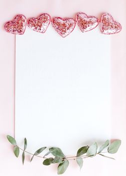 Background with copy space blank on pink background with pink glittered hearts, eucalyptus branch. White paper top view, flat lay, minimal style. Moke up card