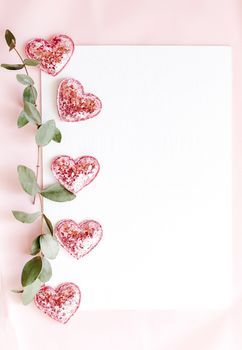 Background with copy space blank on pink background with pink glittered hearts, eucalyptus branch. White paper top view, flat lay, minimal style. Moke up card