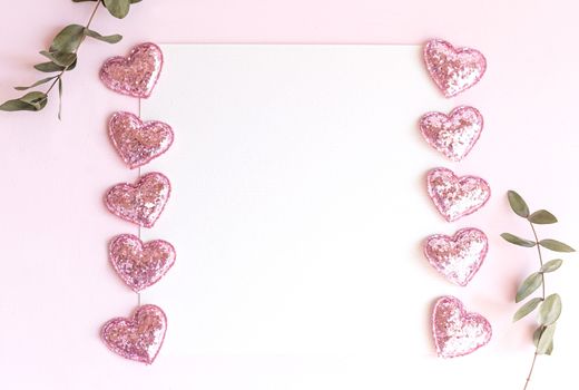 Background with copy space blank on pink background with pink glittered hearts, eucalyptus branch. White paper top view, flat lay, minimal style. Moke up card