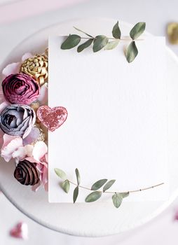 Background with copy space blank on table with glitter heart, eucalyptus branch, flowers and leafs. White paper top view, flat lay, minimal style. Moke up card