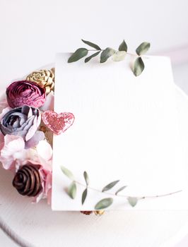 Background with copy space blank on table with glitter heart, eucalyptus branch, flowers and leafs. White paper top view, flat lay, minimal style. Moke up card