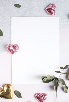 Background with copy space blank on table with glitter heart, eucalyptus branch, flowers and leafs. White paper top view, flat lay, minimal style. Moke up card