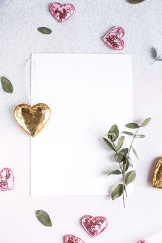 Background with copy space blank on table with glitter heart, eucalyptus branch, flowers and leafs. White paper top view, flat lay, minimal style. Moke up card