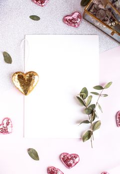 Background with copy space blank on table with glitter heart, eucalyptus branch, flowers and leafs. White paper top view, flat lay, minimal style. Moke up card