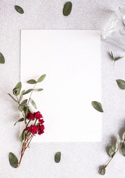 Background with copy space blank on table with glitter heart, eucalyptus branch, flowers and leafs. White paper top view, flat lay, minimal style. Moke up card