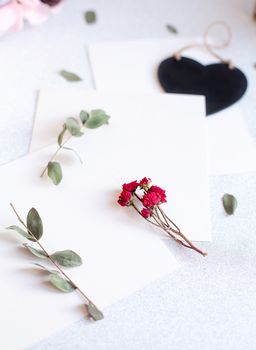 Background with copy space blank on table with black heart, eucalyptus branch, roses flowers and leafs. White paper top view, flat lay, minimal style. Moke up card