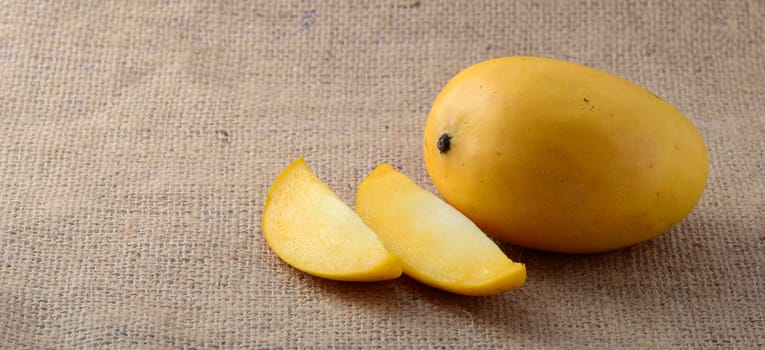 Mango fruit with slice on sack cloth background