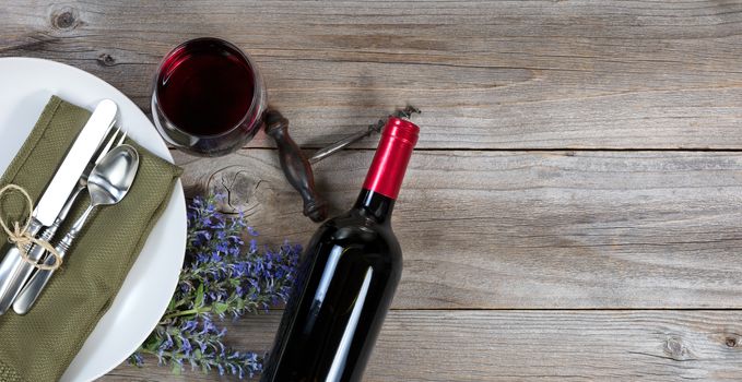 Vintage table setting with fresh flowers and red wine on rustic wood