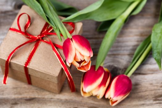 Boxed gift and flowers on stressed wood background