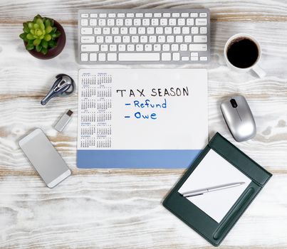 Overhead view of a modern technology devices with tax reminder calendar on white wooden desktop 