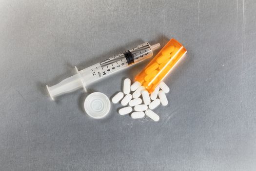 Flat view of painkiller pills with open bottle and syringe. Opioid epidemic concept.