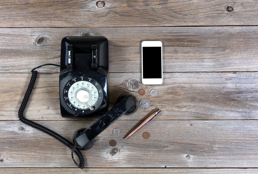 Overhead view of antique phone with modern smartphone on rustic wood 