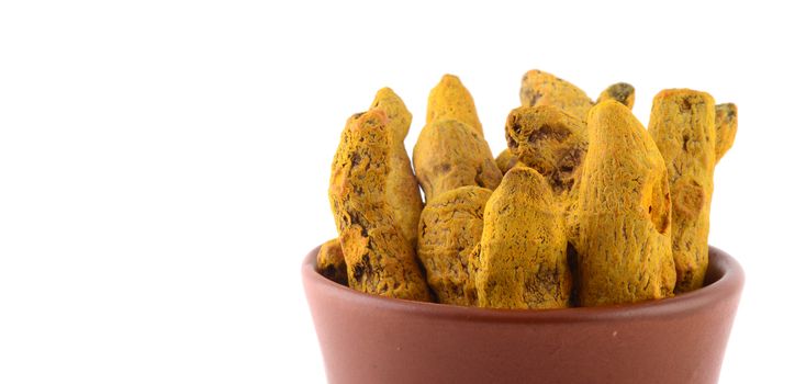 Dry Turmeric roots or barks in clay pot isolated on white background