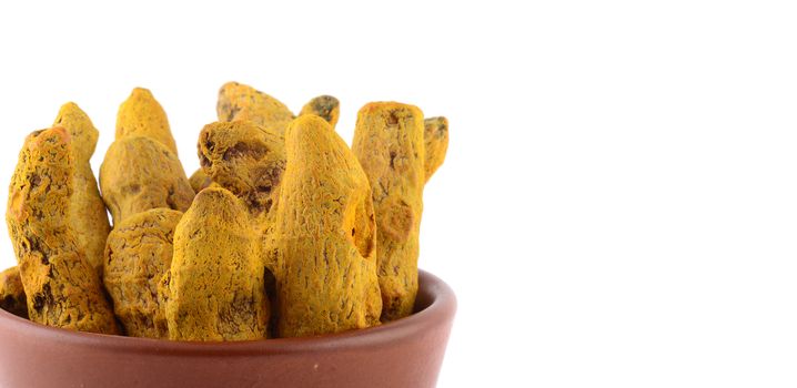 Dry Turmeric roots or barks in clay pot isolated on white background