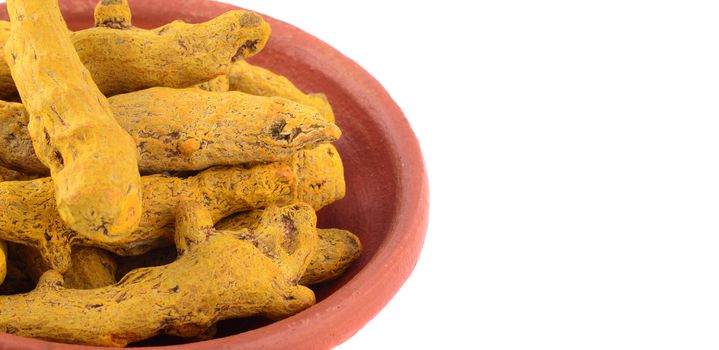 Dry Turmeric roots or barks in clay pot isolated on white background