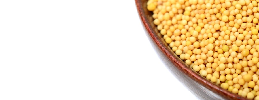 yellow mustard seeds in bowl isolated on white background