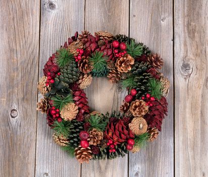 Holiday evergreen and berry wreath on top of rustic wood