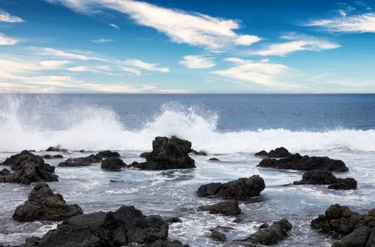 Ocean and rocks with cloudy blue sky 