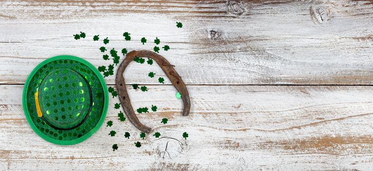 St Patricks day good luck hat and horseshoe with clovers on weathered white wood in overhead view