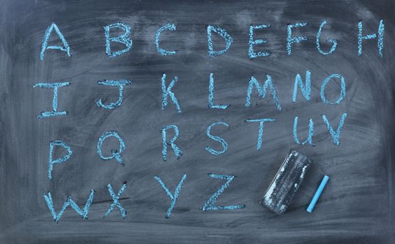 Alphabet blue letters with eraser and chalk on blackboard 