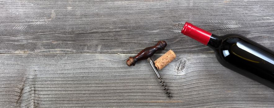 Unopen bottle of red wine with vintage corkscrew on rustic planks 