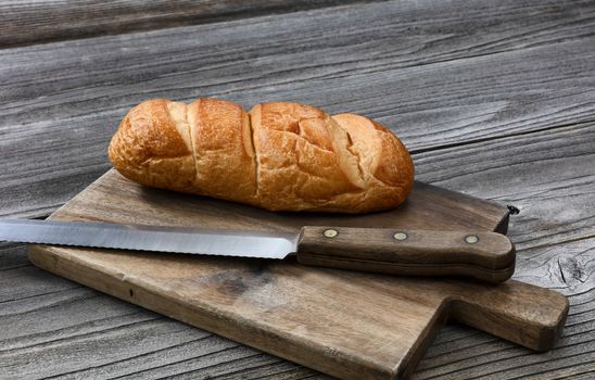 Organic whole wheat loaf with large curated knife on cutting board in close up layout  