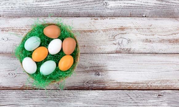 colorful real eggs on artificial green grass in basket for Easter Background 