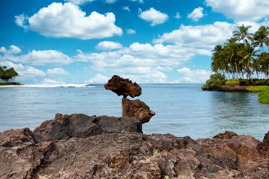 Rough rocks stacked vertically with ocean in background 