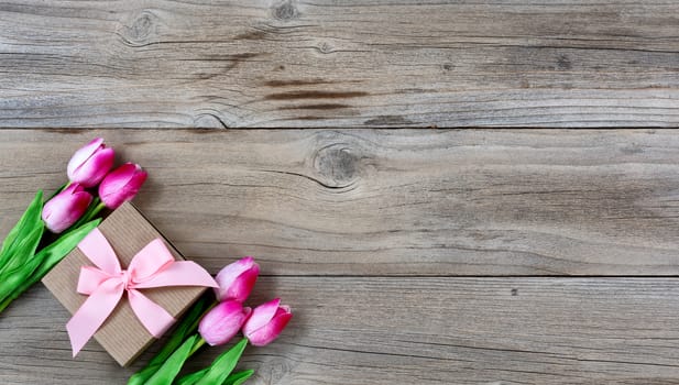 Gift box with pink tulips on rustic wooden boards for Mothers day Background 