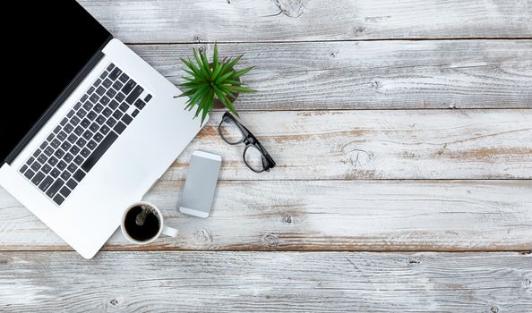 Overhead view of working desktop and smart phone, coffee, reading glasses and baby plant with plenty of copy space 