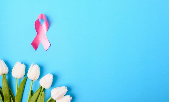 Breast cancer month concept, flat lay top view, pink ribbon and Tulip Flower on blue background with copy space for your text