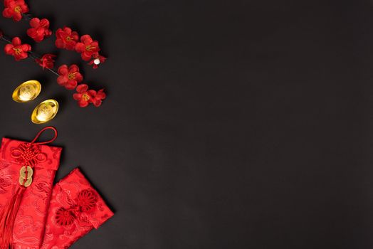 Chinese new year concept, flat lay top view, Happy Chinese new year with Red envelope and gold ingot (Character "FU" means fortune, blessing, wealth) on black background with copy space for your text