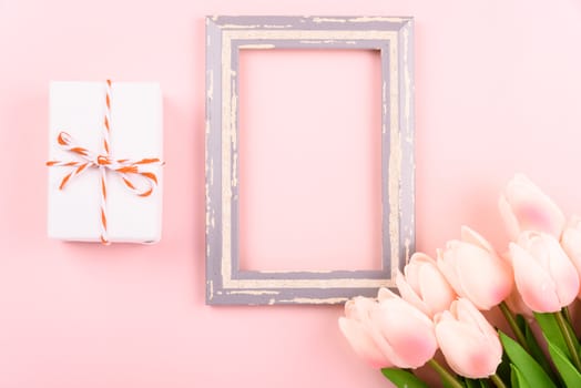 Happy Women's Day, Mother's Day concept. top view flat lay photo frame, gift box and Tulip flower on pink background, copy space for your text