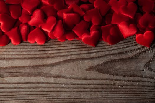Valentine's day many red silk hearts on wooden background, love concept