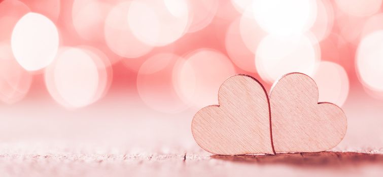Two handmade wooden hearts on beautiful pink bokeh background. Vintage style. Love Valentine's Day concept.
