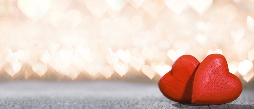 Two red wooden hearts symbol of love on background with beautiful bokeh party lights, Saint Valentine Day celebration