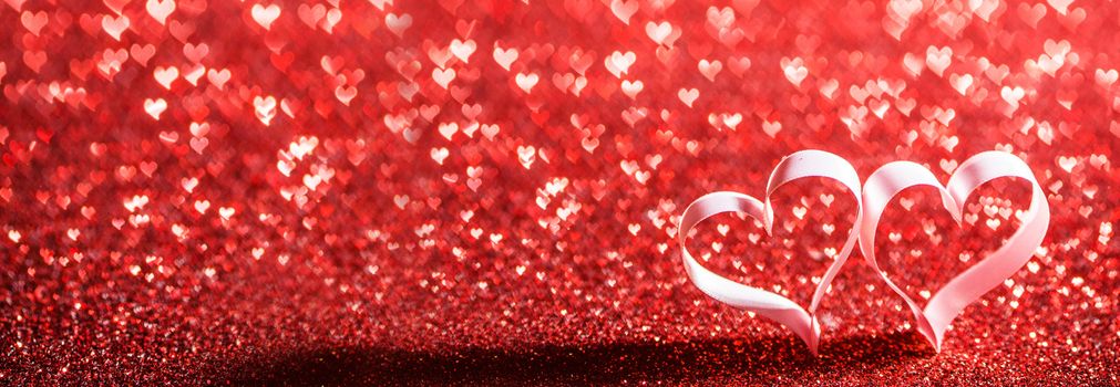 Two red ribbon hearts on glitter background with copy space for text, Valentines day concept