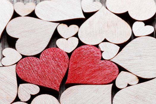 Many wooden colorless hearts background, two red special ones true love concept