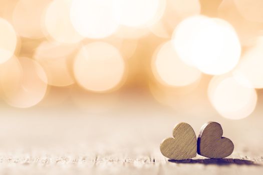 Two handmade wooden hearts on beautiful golden bokeh background. Vintage style. Love Valentine's Day concept.
