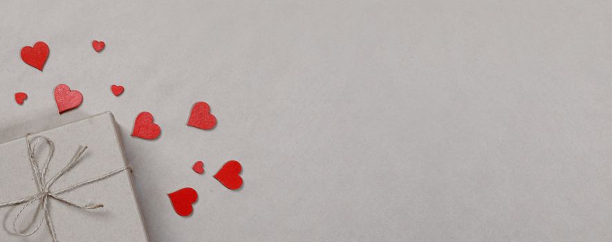 Box with gifts wrapped in brown craft paper and red paper hearts Valentines day concept