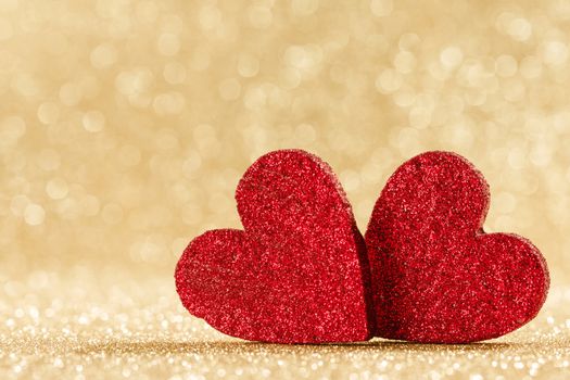 Two small handmade red glitter hearts on bright golden lights bokeh background Valentines day card