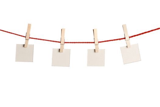 Set of four red blank paper notes held on a string with clothespins isolated on white background