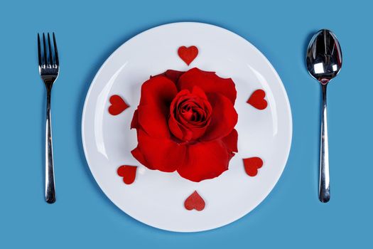 Cutlery set plate rose flower and hearts on blue background Valentine day romantic dinner concept