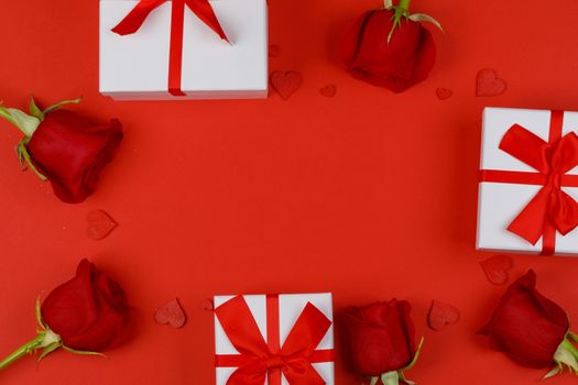Red rose flowers gifts hearts and gifts composition on red background top view with copy space. Valentine's day, birthday, wedding, Mother's day concept. Copy space