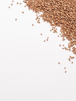 Buckwheat with copy space. Brown raw buckwheat grain on white background. Top view or flat lay. Copy space. Healthy food and diet concept. Buckwheat background. Vertical