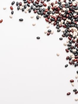 Top view of raw mixed beans on white background. Mixed of uncoocked black, red and white beans with copy space isolated on white. Food background. Vegan protein concept. Flat lay. vertical