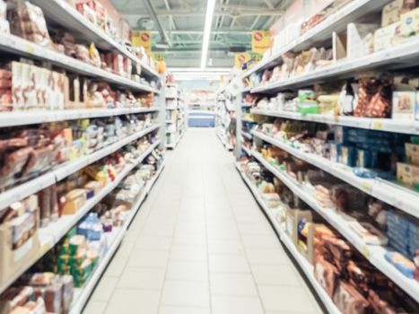 Abstract blurred supermarket aisle with colorful shelves and unrecognizable customers as background